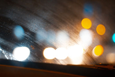 Defocused image of illuminated lights seen through wet window