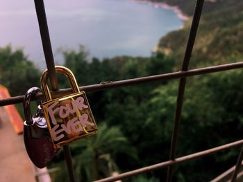 Close-up of padlocks on railing against sky