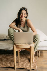 Young happy female student studying online using laptop and headphones.