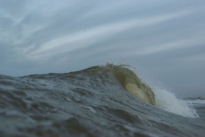 Sea waves splashing on shore against sky