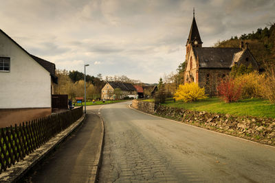 Road amidst buildings against sky