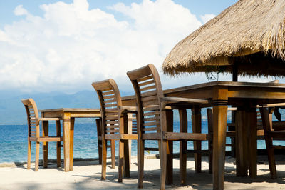 Chairs and table on beach against sky