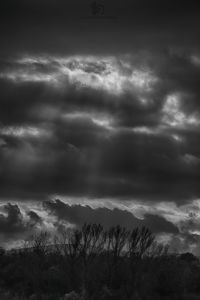 Low angle view of storm clouds over silhouette landscape