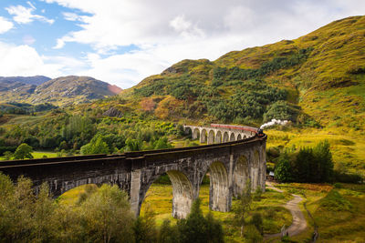 Arch bridge over mountains against sky