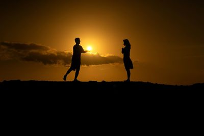 Silhouette man standing against orange sky
