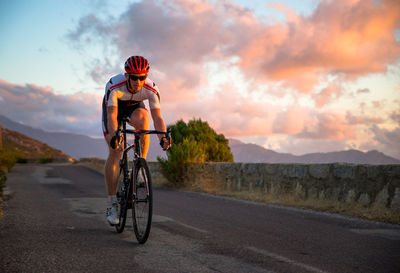 Man riding bicycle on road against sky