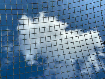 Low angle view of glass building against blue sky