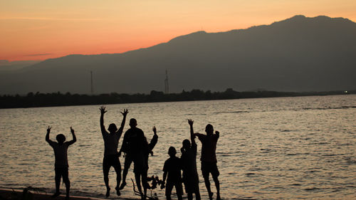 Silhouette people at beach against sky during sunset