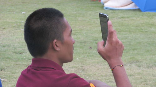 Close-up of man using mobile phone in grass