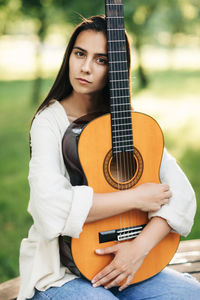 Portrait of a beautiful musician girl with a guitar in the park. girl-musician, music, hobby. 