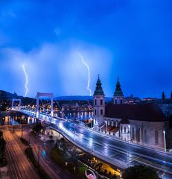 Panoramic view of light trails in city against sky at night