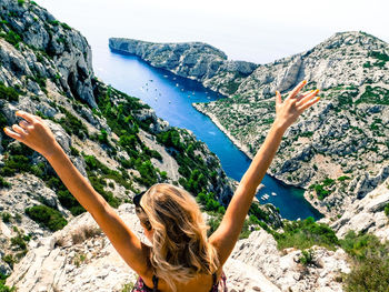 Woman standing on rock by mountain against sky