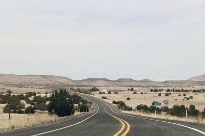 Road passing through landscape against sky