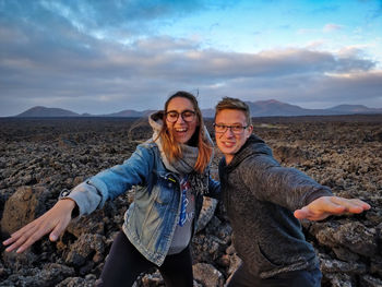 Smiling friends flying on land against sky