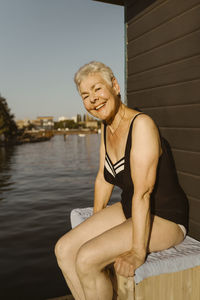 Portrait of young woman sitting against lake