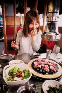 Excited woman looking at meat grilling on barbecue