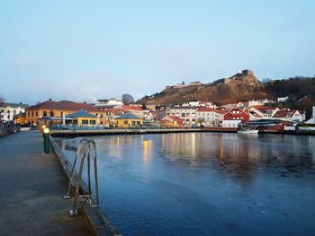 Houses by river in town against clear blue sky