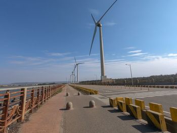Wind turbines by road against sky
