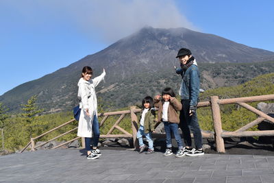 Rear view of people standing on mountain against sky