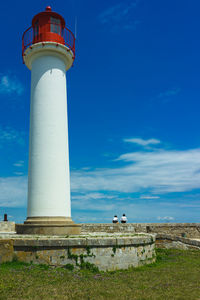 Low angle view of lighthouse by building against sky