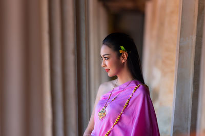 Young woman wearing traditional clothing looking through window