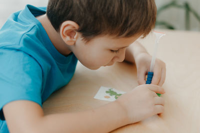 Close up of little boy creating a diamond mosaic, selective focus.