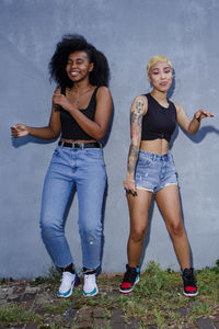 Two young women friends dance together in identical dress outside