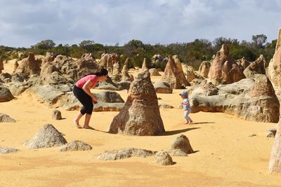 People on rock formations against sky