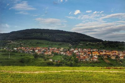 Scenic view of green landscape and houses against sky