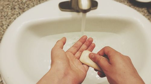 Cropped image of person washing hands at sink