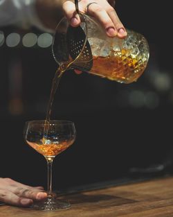 Midsection of person pouring wine in glass