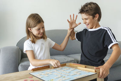 Siblings playing board game on table at home