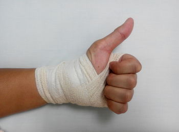 Cropped image of hand with bandage on white background