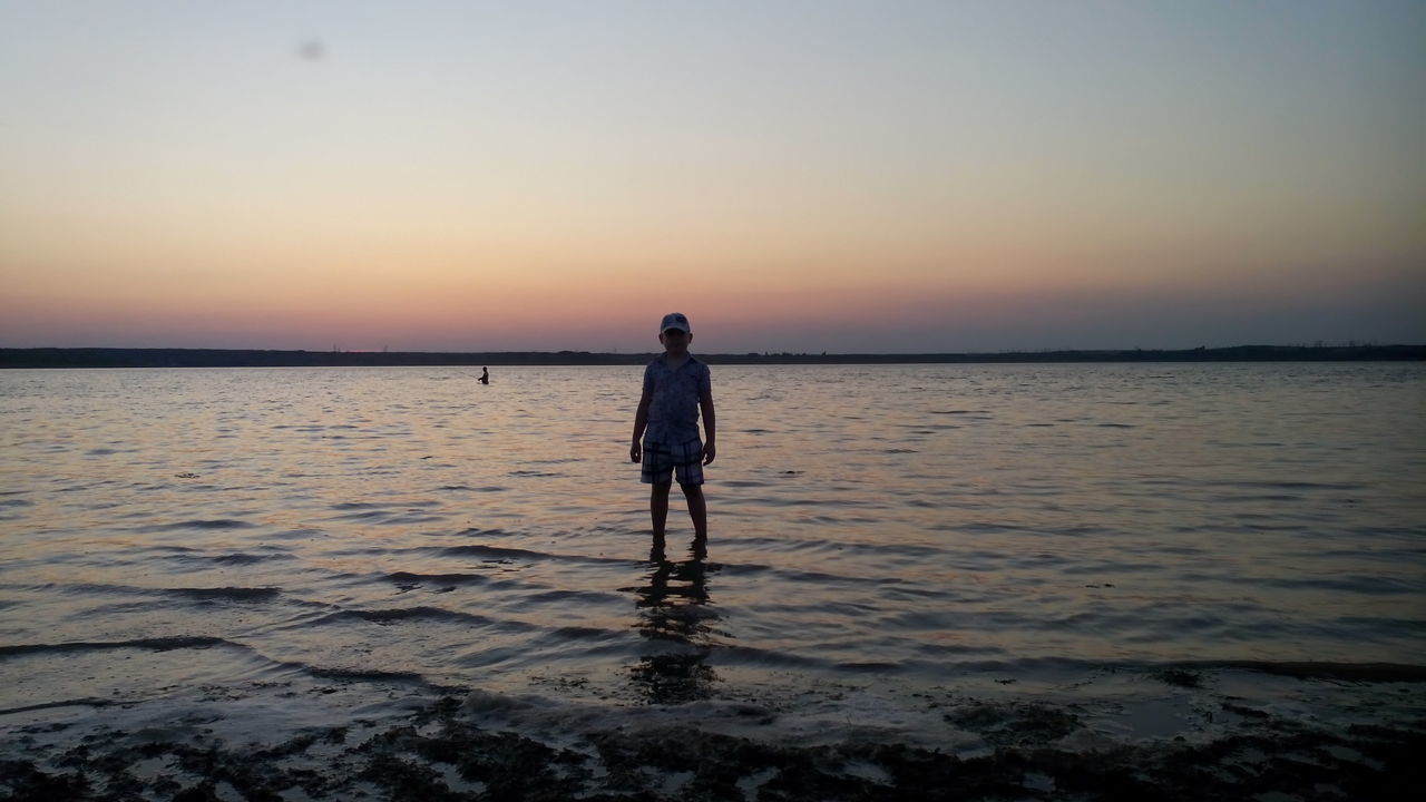 water, sunset, sea, beach, standing, full length, lifestyles, leisure activity, shore, tranquil scene, silhouette, scenics, tranquility, beauty in nature, horizon over water, rear view, clear sky, nature