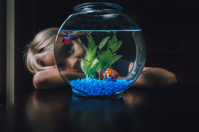 Cute girl leaning on table by fishbowl