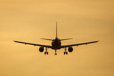 Low angle view of airplane flying against sky during sunset