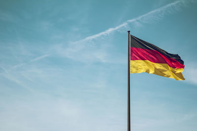 Low angle view of german flag against blue sky