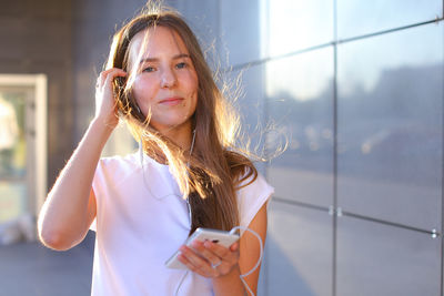 Portrait of young woman standing against window