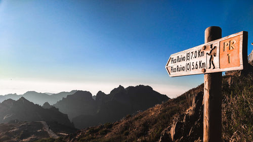 Information sign by mountains against clear sky