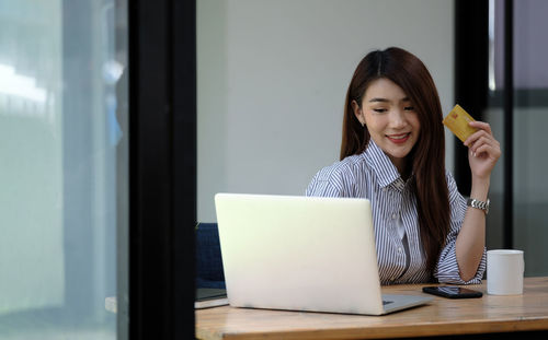 Young woman using phone while sitting on table
