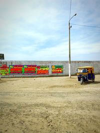 Posters on wall by road against sky in city