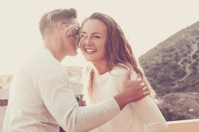 Smiling couple embracing while standing in balcony