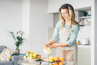 Portrait of young woman holding fruits at home