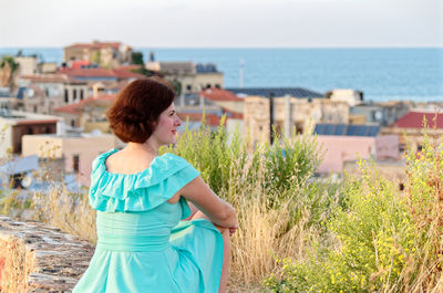 Rear view of woman sitting against buildings