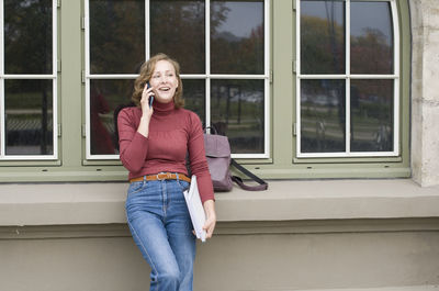 A young girl back to school, stands with a backpack and talks on the phone