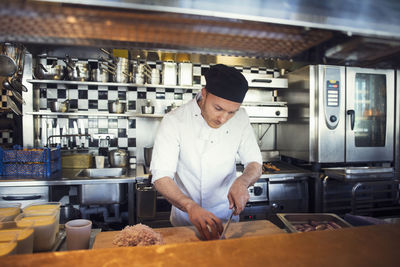 Male chef chopping onion cutting board in restaurant kitchen