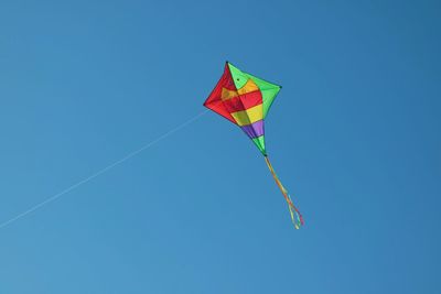 Low angle view of kite flying against clear blue sky