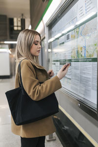 Woman with purse using smart phone at subway station