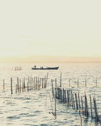 Wooden posts in sea against clear sky
