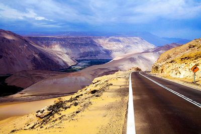 Scenic view of road leading towards mountains against sky